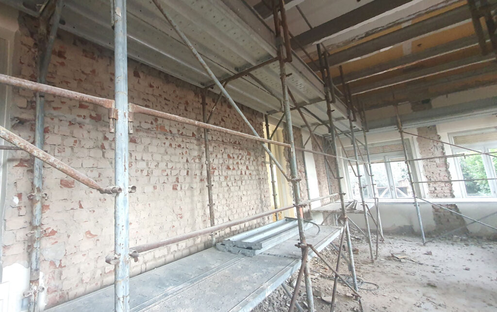 Interno del cantiere di rinforzo sismico dell'asilo nido di Vimercate: ponteggi metallici per la posa del sistema FRCM sui maschi murari